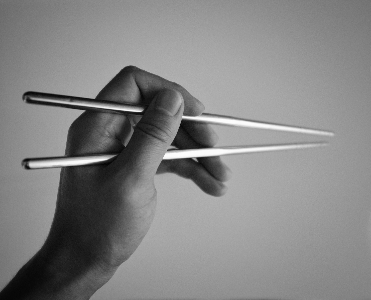 person holding sticks in grayscale photography