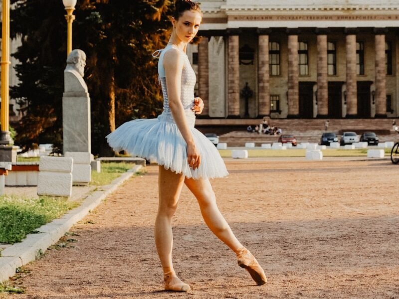 ballerina standing on pathway near buildings